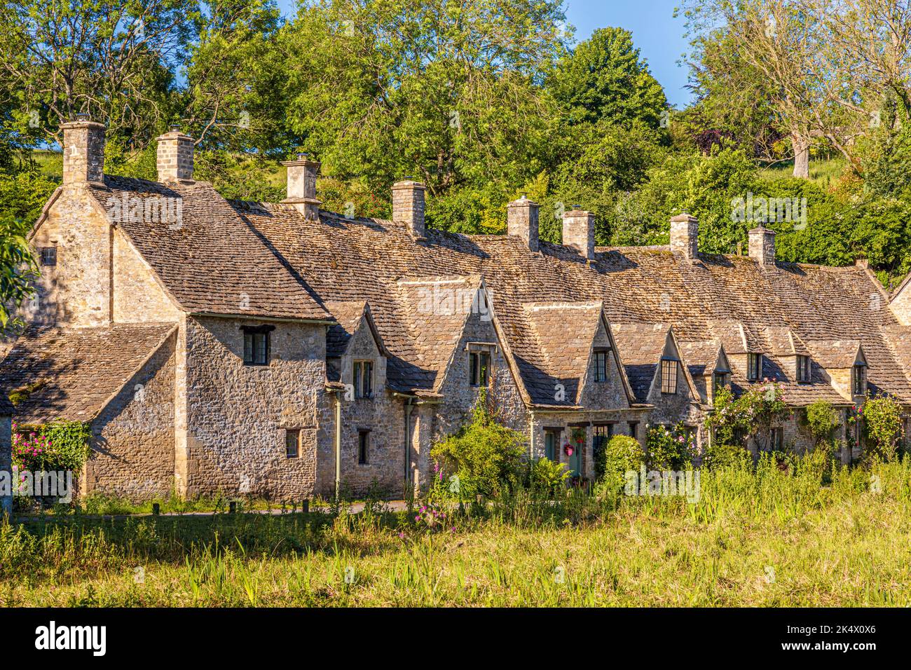 Im Hochsommerlicht am frühen Morgen in der Arlington Row im Cotswold-Dorf Bibury, Gloucestershire, England Stockfoto