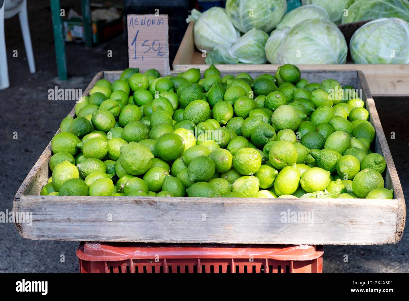 Frisch gepflückte Zitronen der Saison, Citrus limon, zum Verkauf an einem offenen Marktstand in Rhodos Griechenland. Die Zitronen werden in einer Schachtel angezeigt und sind preislich Stockfoto