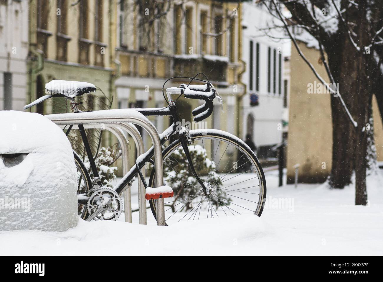 Altes Oldtimer-Fahrrad, mit einer Kette gebunden und vom Schnee bedeckt, der auf der Straße der Altstadt von Vilnius geparkt ist Stockfoto