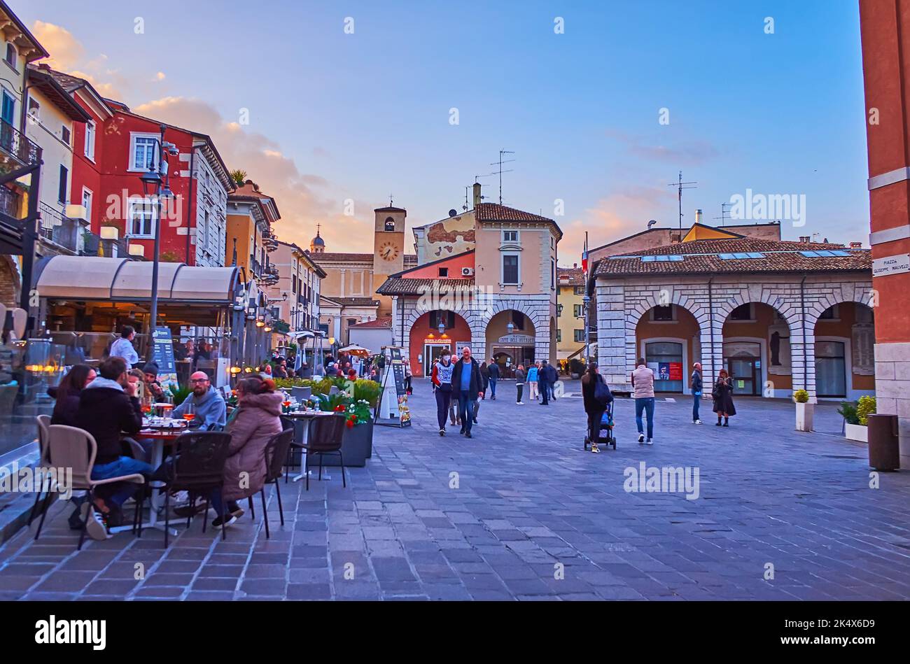 DESENZANO DEL GARDA, ITALIEN - 10. APRIL 2022: Abendliche Piazza Giuseppe Malvezzi mit überfüllten Terrassen mit Restaurants und Bars, am 10. April in Desenzano Stockfoto