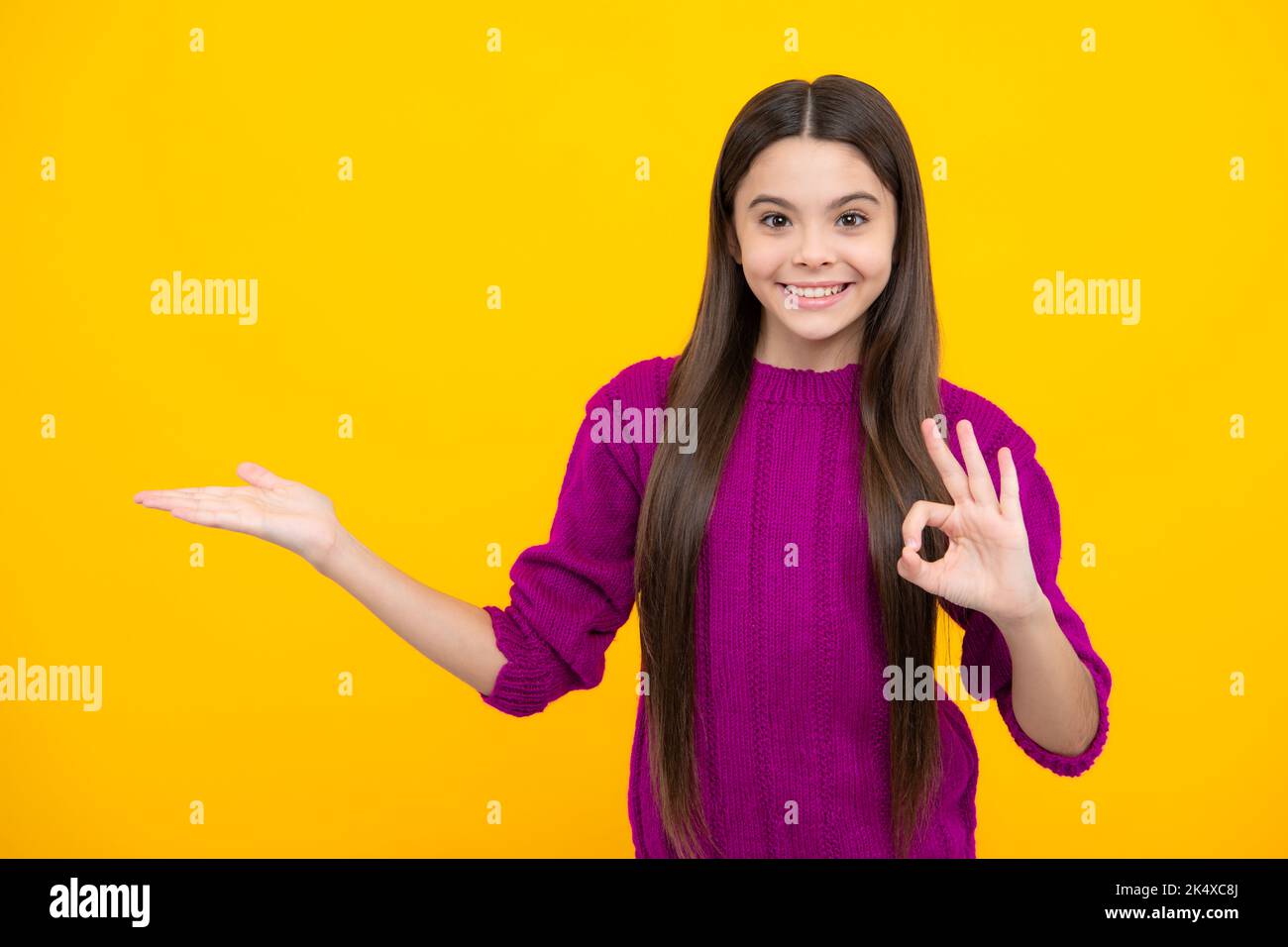 Positive Teenager Kind zeigt sich mit fröhlichem Ausdruck beiseite, zeigt erstaunlich auf leeren leeren Raum. Werbung und Mockup. Stockfoto