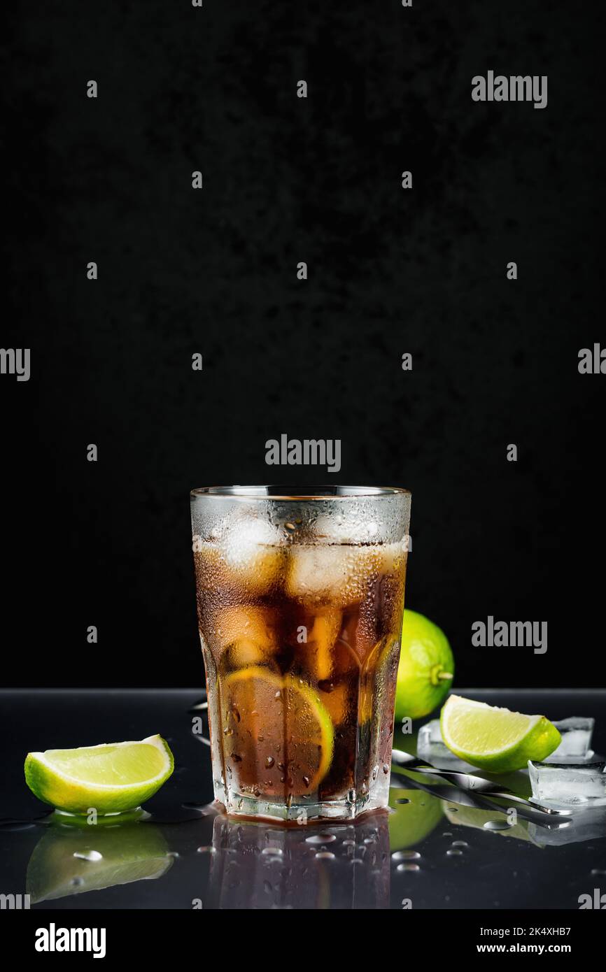 Cuba Libre Cocktail mit Limette auf schwarzem Hintergrund. Stockfoto
