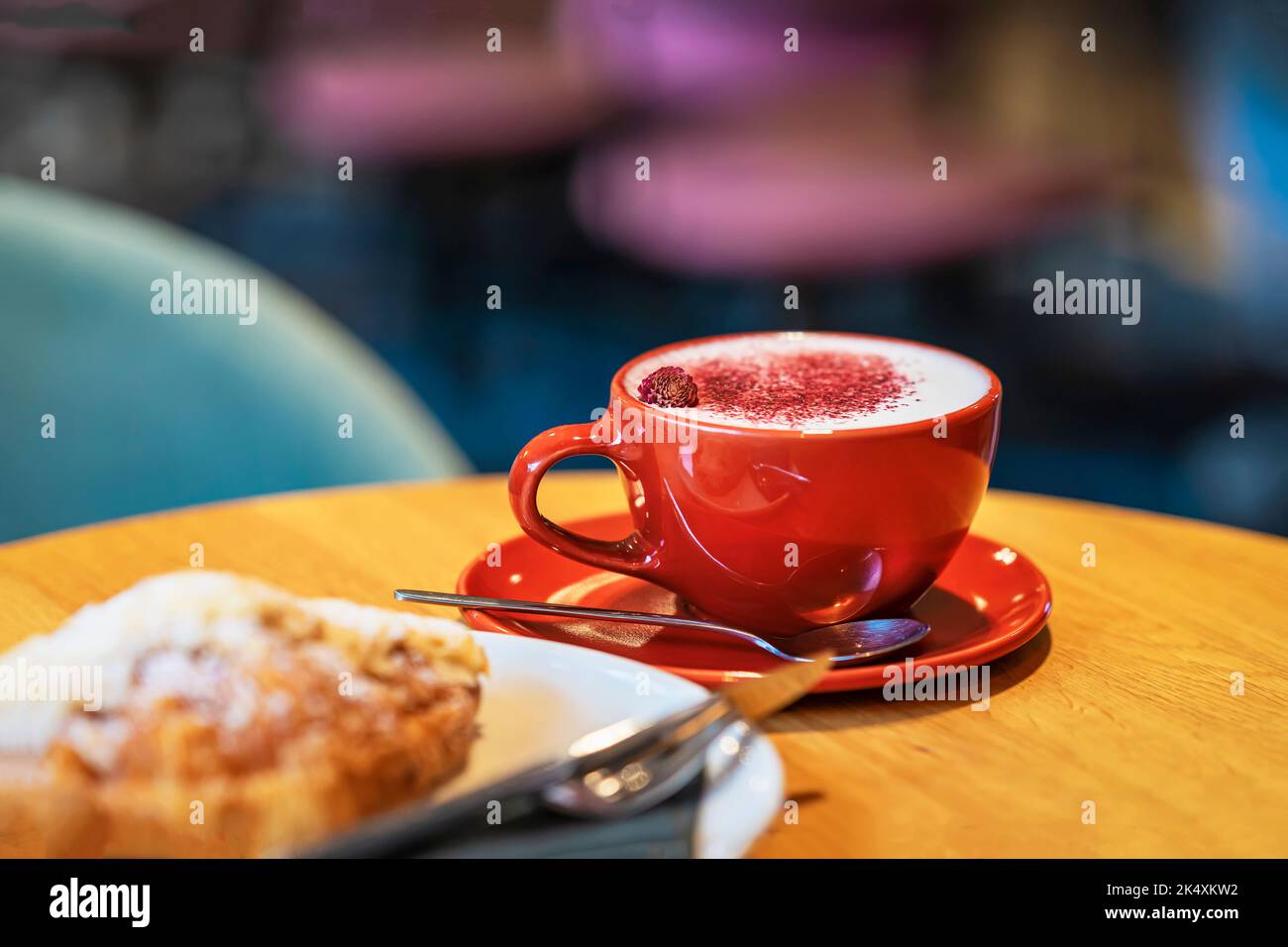 Leuchtend rote Tasse mit köstlichem Cappuccino aus nächster Nähe auf dem Tisch im Kaffeehaus Stockfoto