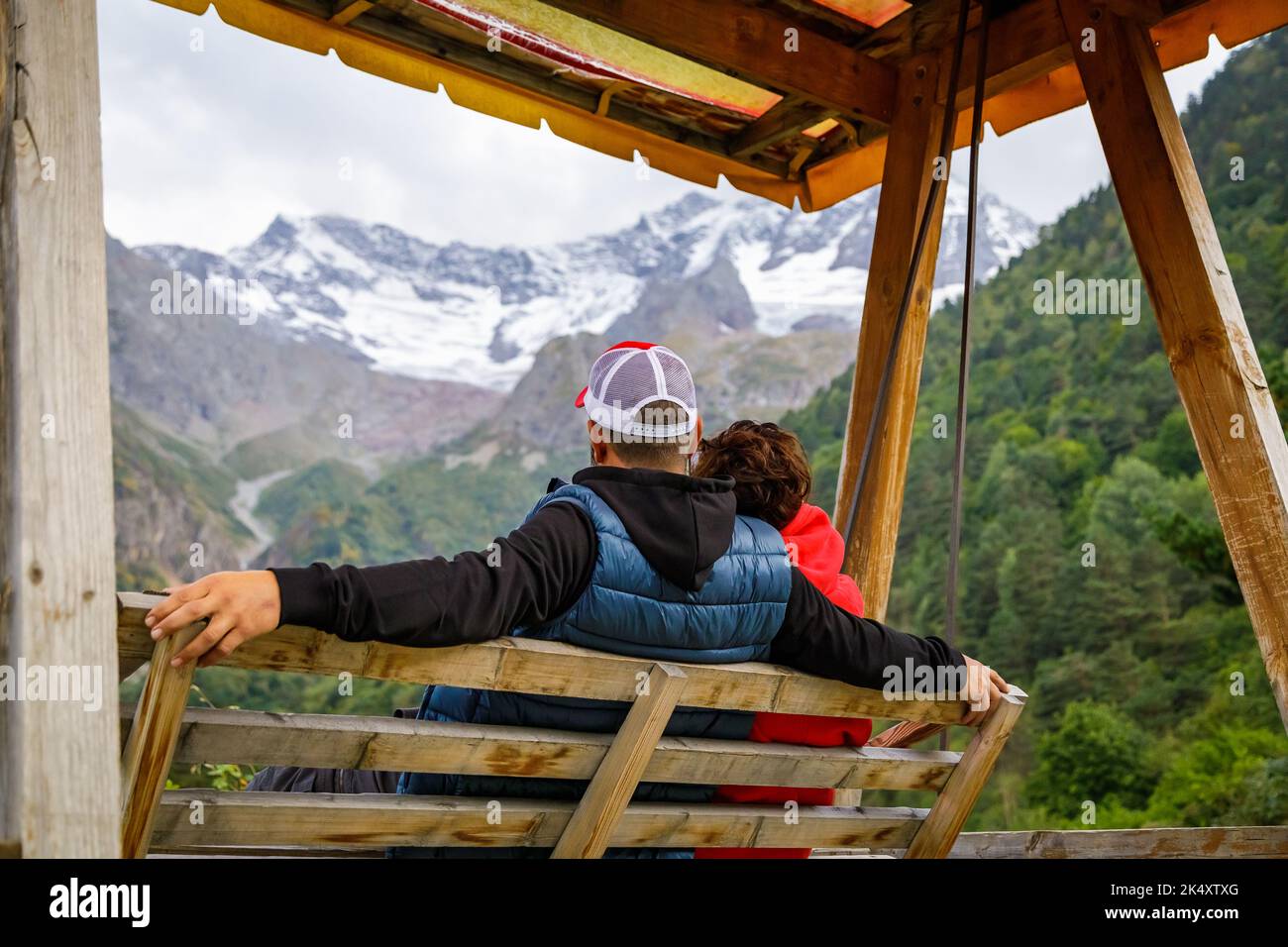 Ein Mann und eine Frau schwingen auf einer Schaukel hoch in den Bergen. Entspannen Sie sich und genießen Sie die Natur Stockfoto
