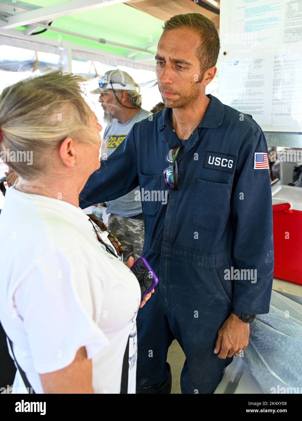 Julian Bell, Chief Warrant Officer der US-Küstenwache, spricht mit einem Bewohner von Pine Island, Florida, am 2. Oktober 2022. Die Streikkräfte brachten Menschen in Not nach dem US-Bundesstaat Florida, um Schutz und Ressourcen zu suchen. Foto der US-Küstenwache von Petty Officer 3. Klasse Ian Gray. Stockfoto