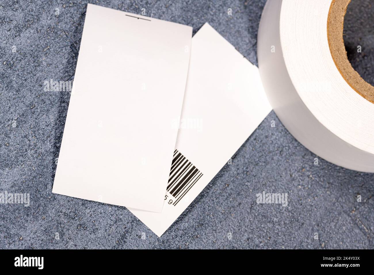 Nahaufnahme eines weißen, weißen Kleiderschildes und eines Tags mit einem Barcode auf einem blauen Tisch Stockfoto