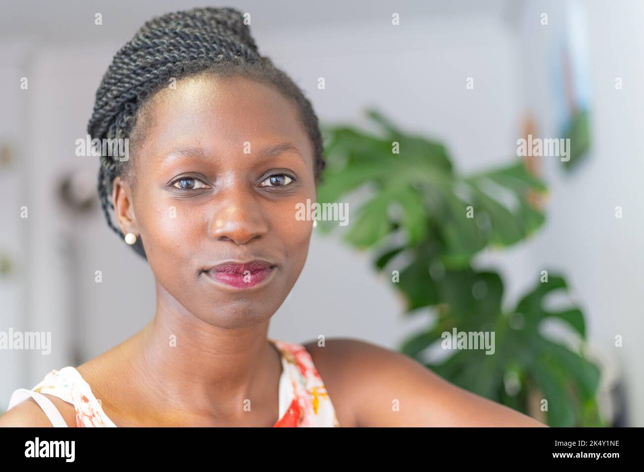 Junge Frau mit einem geblümten Kleid, die in die Kamera schaut Stockfoto