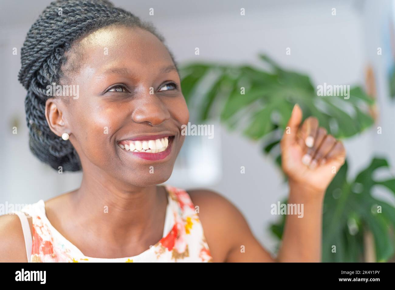 Junge Frau mit einem blumigen Kleid, die lächelt und feiert Stockfoto