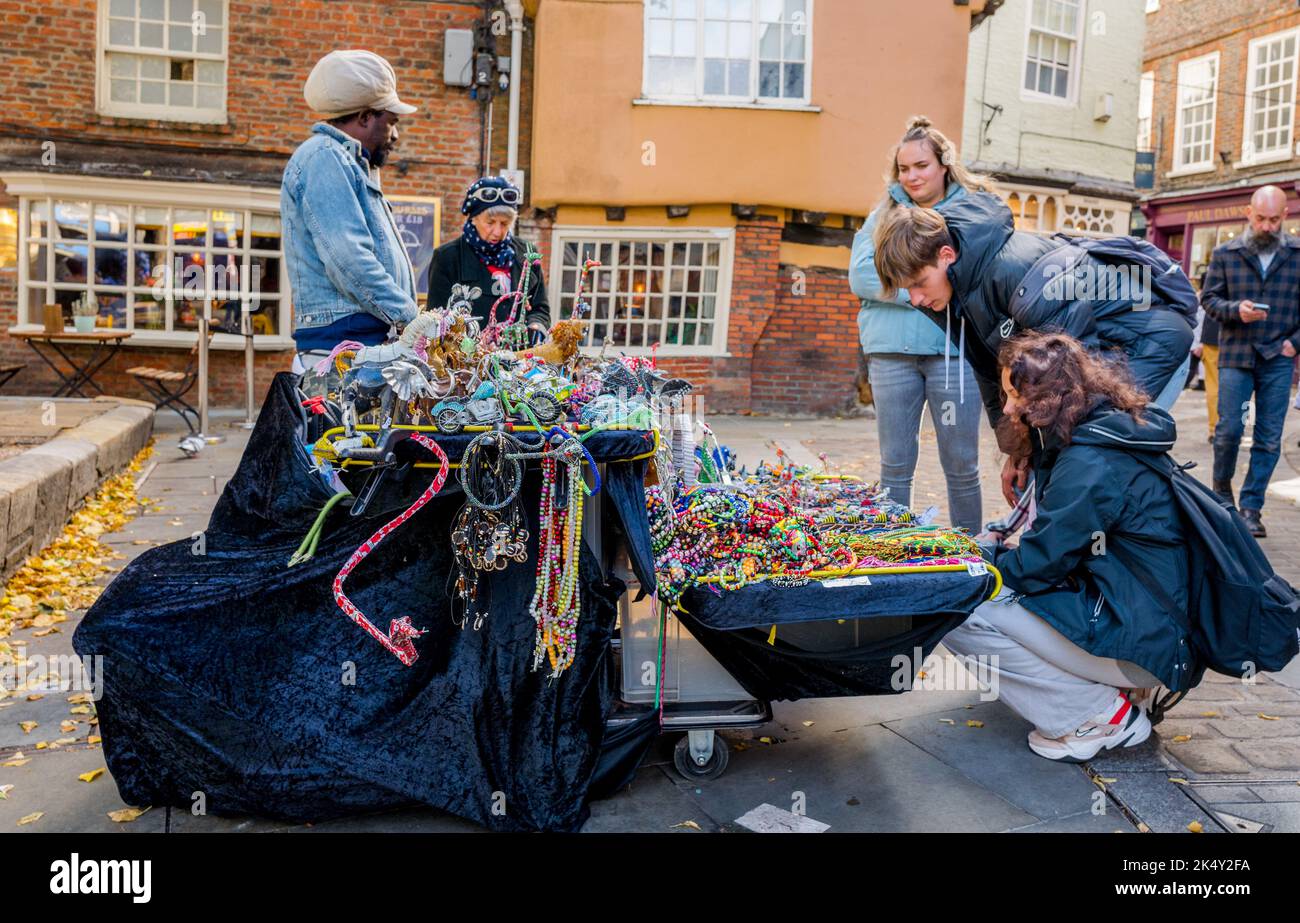 Einziger Straßenhändler, der Schmuckstücke, Perlen, Armbänder usw. von einem überdachten Trolley in der mittelalterlichen Stadt York verkauft. Stockfoto