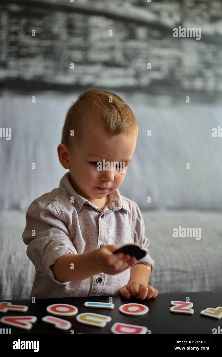 Porträt eines niedlichen kleinen Jungen, der mit Buchstaben und Zahlen auf einem Tisch spielt Stockfoto