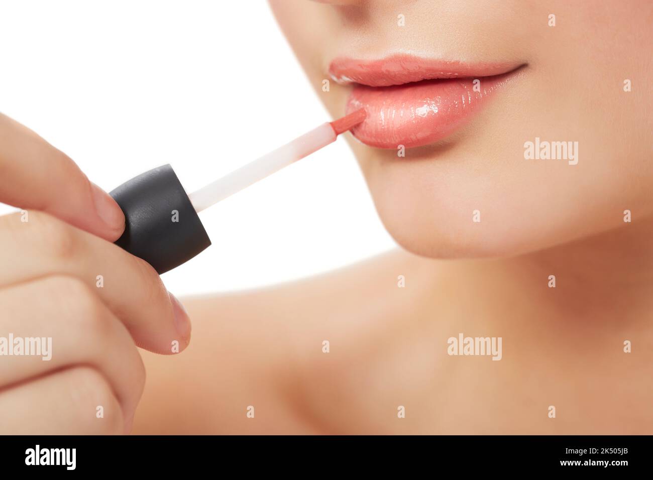 Perfekter Put. Kurze Nahaufnahme einer jungen Frau, die Lipgloss auf ihre Lippen auflegt. Stockfoto