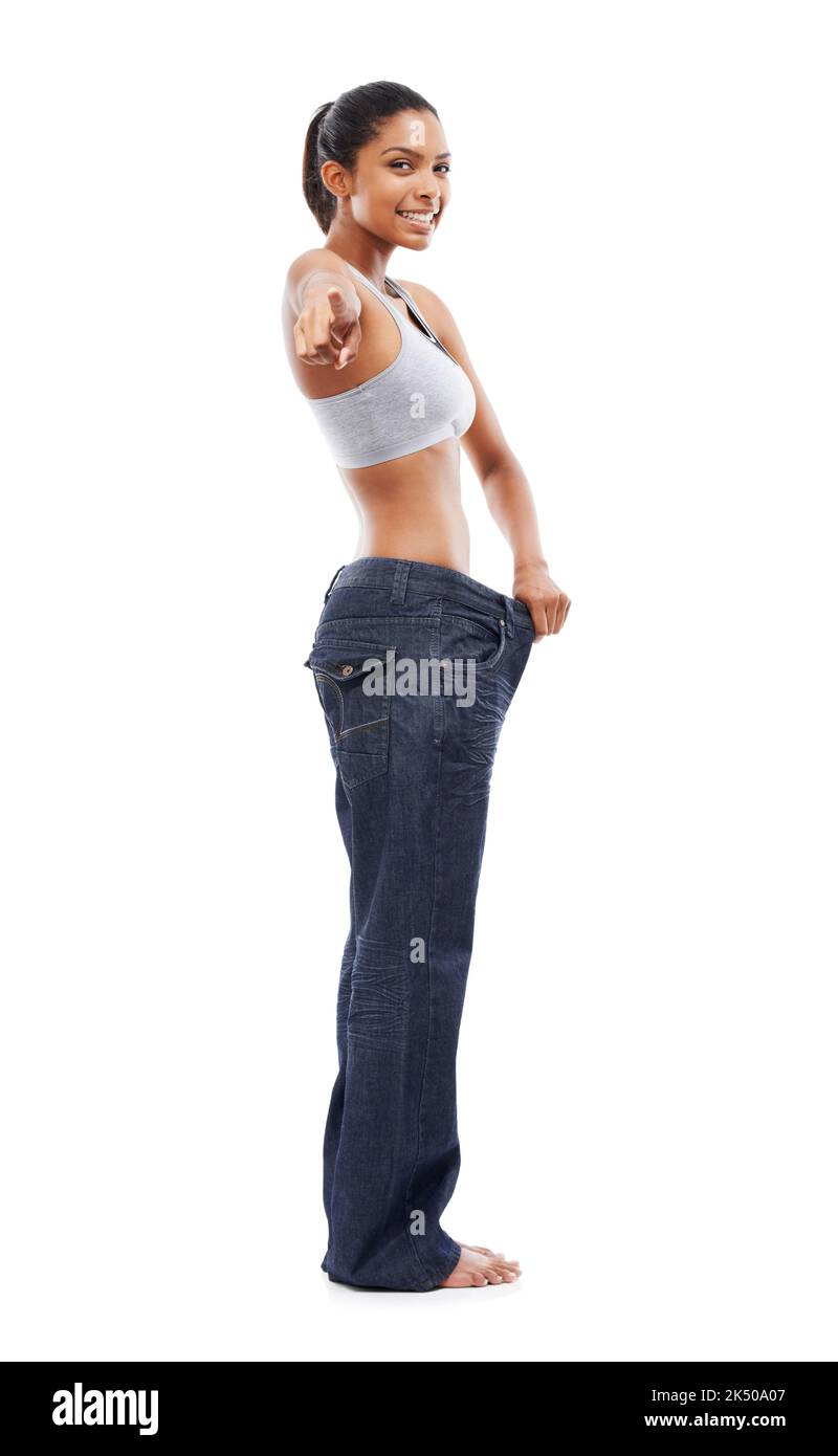 Fordert Sie heraus, den Flab zu verlieren. Eine wunderschöne junge Frau in einer übergroßen Hose, die auf Sie zeigt. Stockfoto