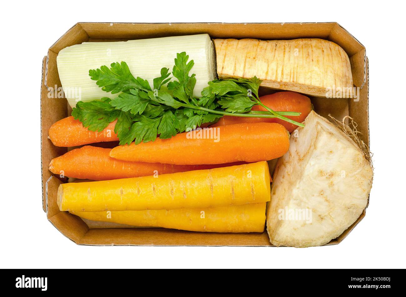 Frische Wintersuppe, ungeschnitten und vorverpackt, in einem Papptablett, von oben, isoliert über weiß. Karotten, Sellerie, Pastinaken, Lauch und Petersilie. Stockfoto