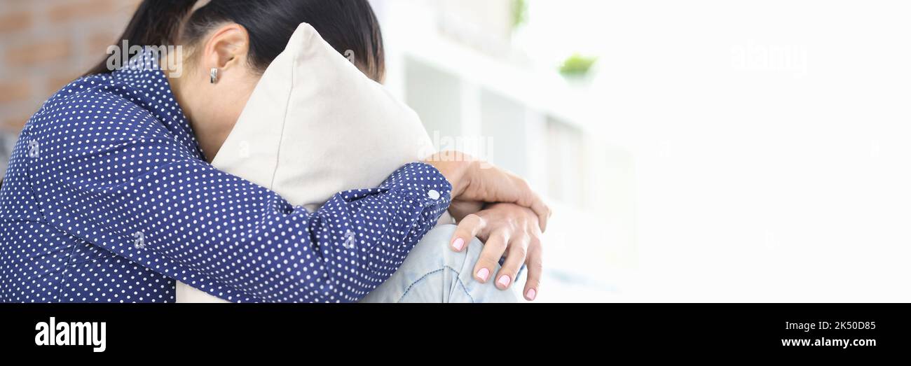 Verärgert Frau sitzt mit Kopf in Kissen begraben Stockfoto