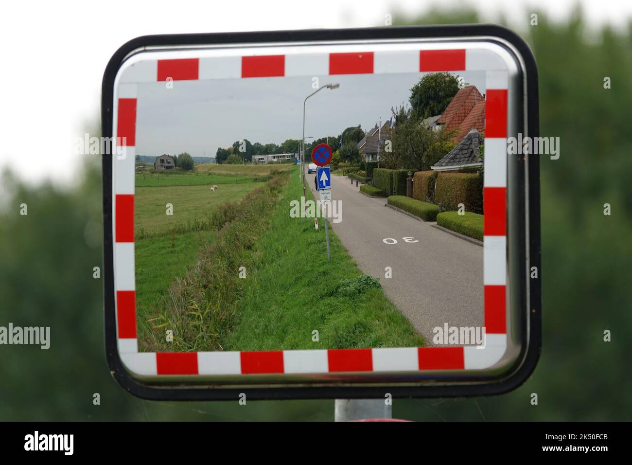 Blick auf eine Landstraße in Elburg, Niederlande durch einen rechteckigen Straßenspiegel Stockfoto