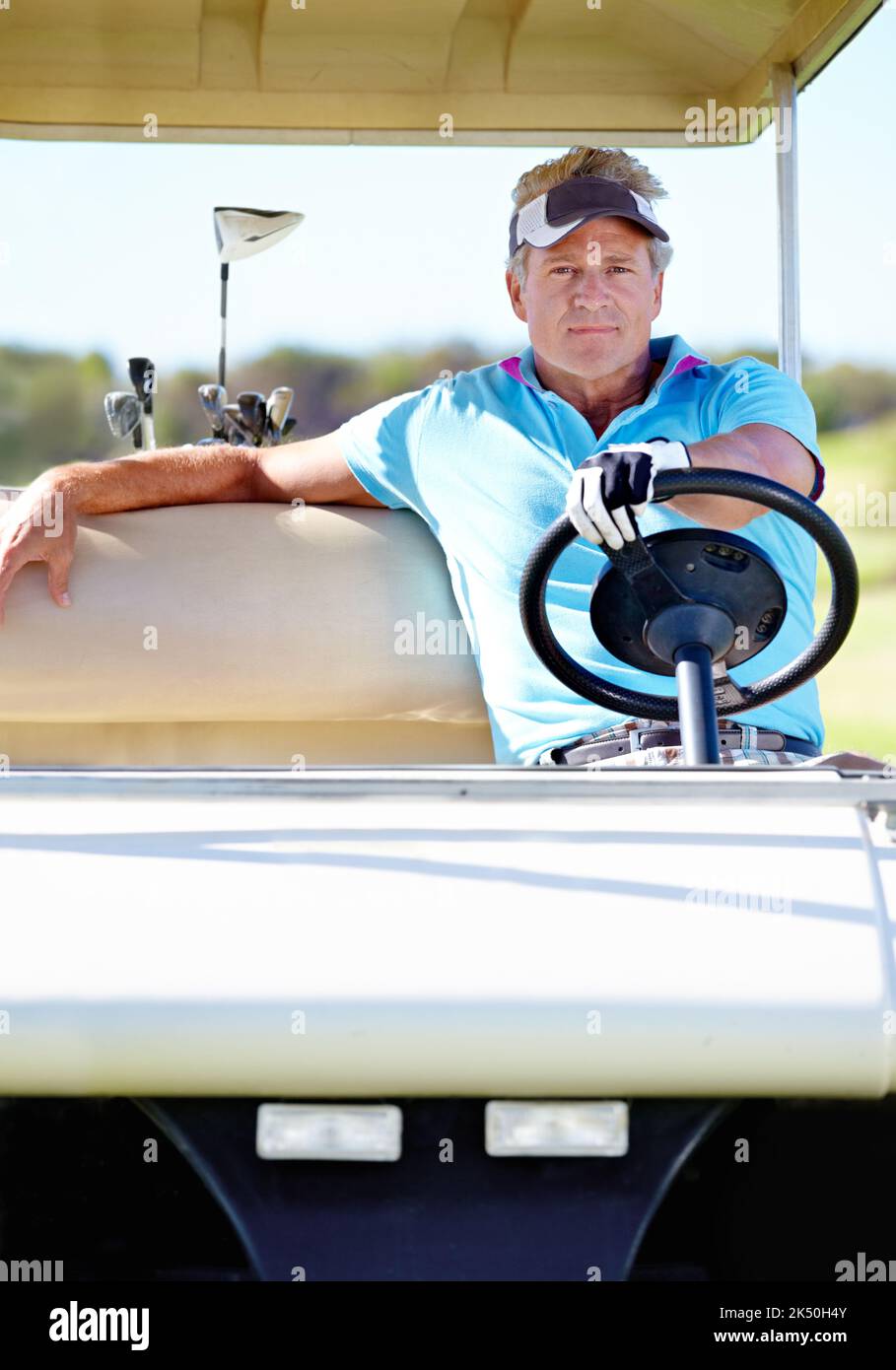 Das ist wirklich Entspannung Übung. Ein reifer Mann sitzt hinter dem Steuer eines Golfwagens und schaut auf die Kamera. Stockfoto