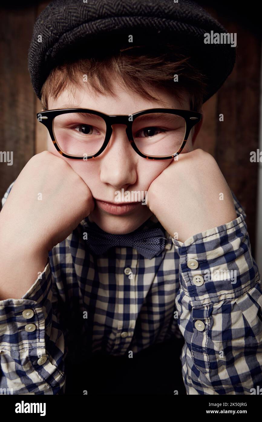 Ich bin so gelangweilt. Kleiner Junge in Retro-Kleidung, der eine Brille mit gelangweilter Ausstrahlung trägt. Stockfoto
