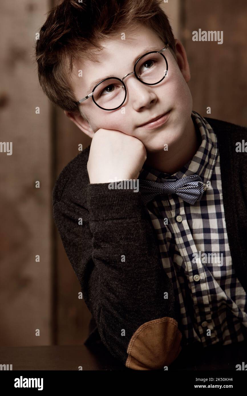Über die Zukunft nachdenken. Kleiner Junge in Retro-Kleidung, der eine Brille mit nachdenklicher Ausstrahlung trägt. Stockfoto