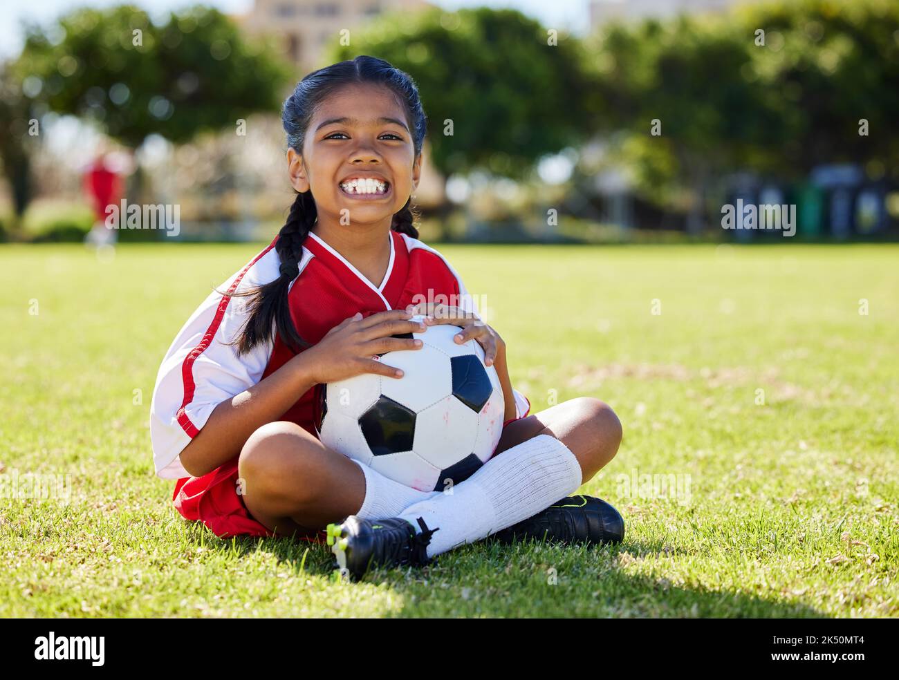 Sport, Kinder und Mädchen Fußballspieler entspannen sich auf Gras mit Fußball, glücklich und aufgeregt beim Training. Fitness, Lächeln und Porträt des indischen Kindes auf Stockfoto