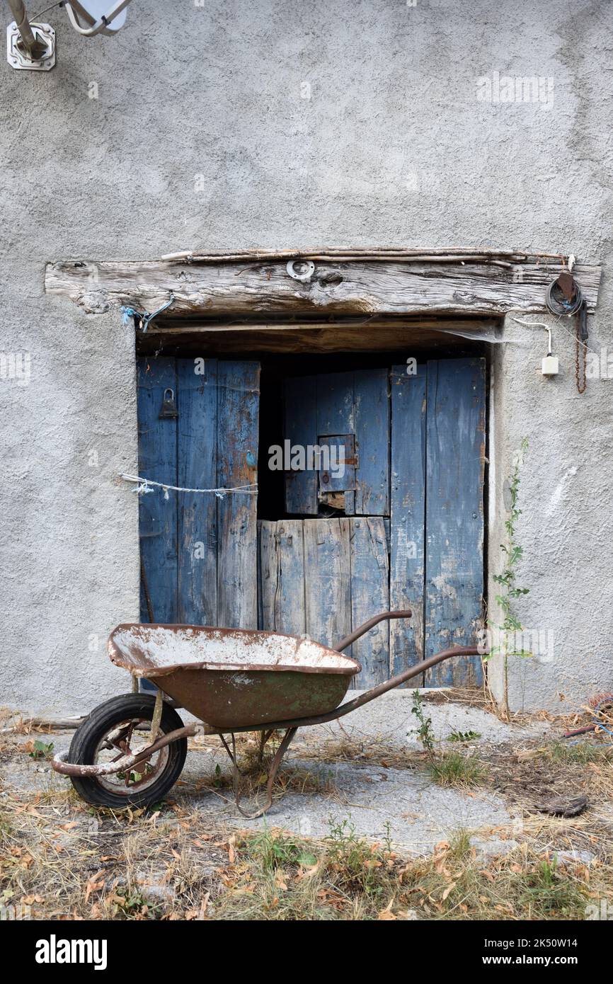 Old Barn Door und Rusty Wheelbarrow Stockfoto