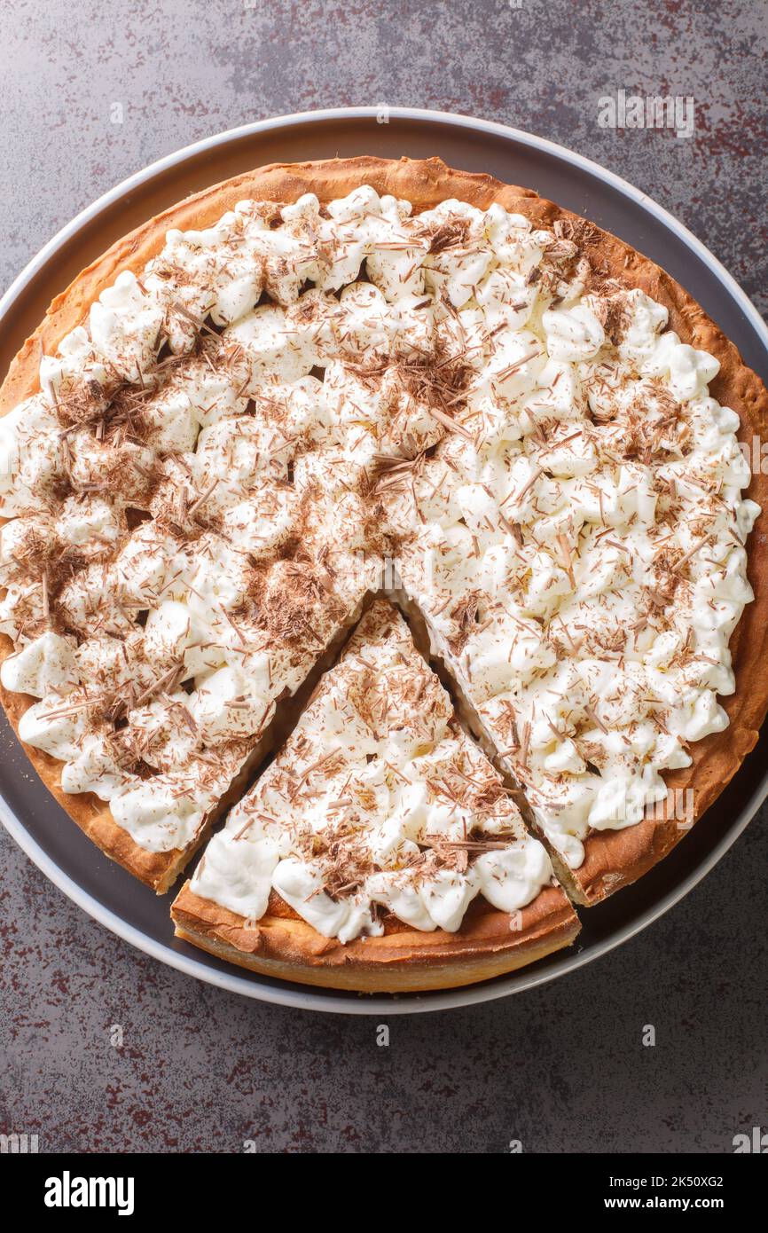Rijstevlaai Dutch Reispudding-Torte mit Schlagsahne und Schokoladenchips in Nahaufnahme auf einem Teller auf dem Tisch abstücken. Vertikale Draufsicht von oben Stockfoto