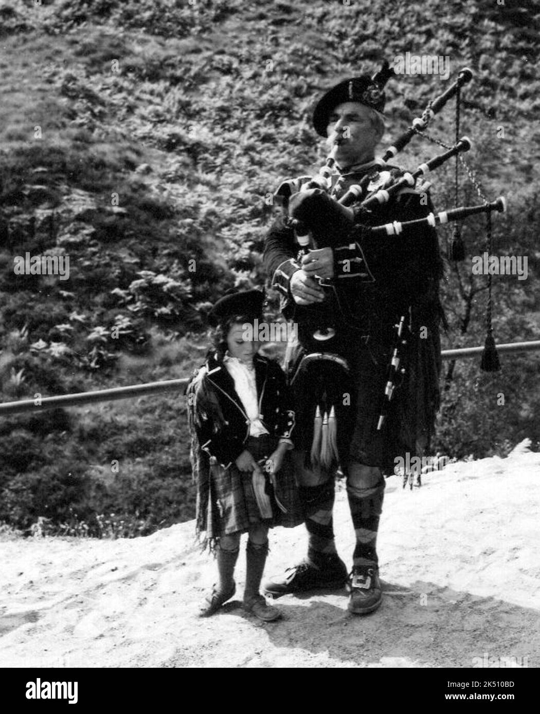 Piper und seine Tochter spielen 1950s für Touristen in Glencoe, Schottland Stockfoto