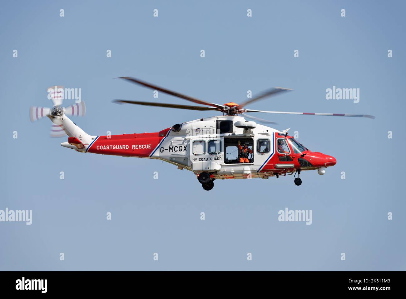 HM Coastguard-Crewman winkt vor der Tür seines Leonardo AW189 Helicopters, als er beim Royal International Air Tattoo von der Menge fliegt Stockfoto