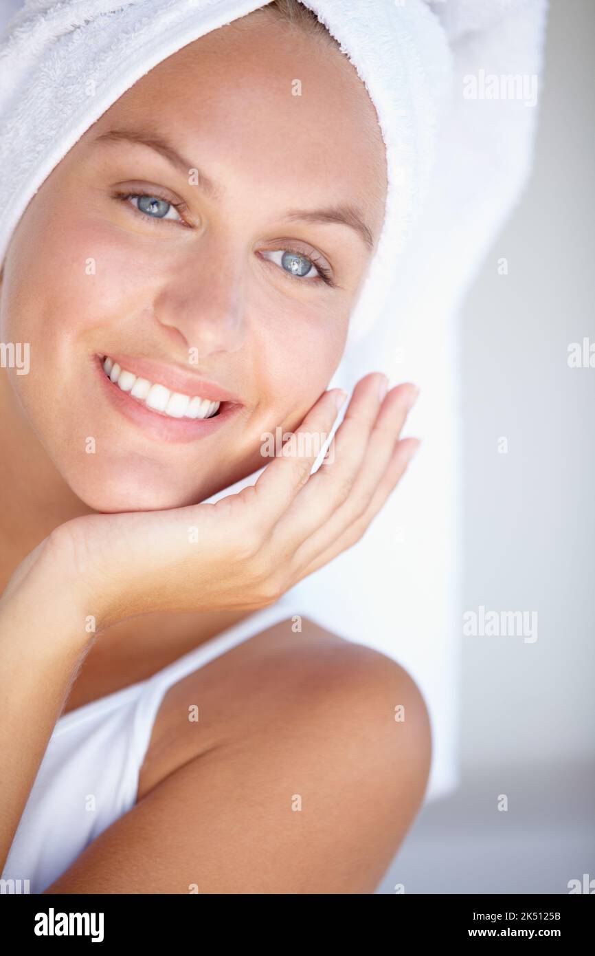 Das nach dem Duschen...Nahaufnahme einer jungen Frau, deren Haare in ein Handtuch gewickelt sind, das ihre Wange berührt. Stockfoto
