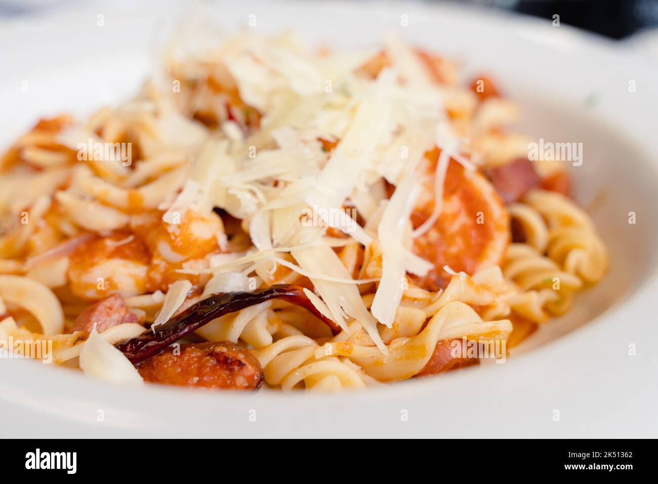 Nahaufnahme von Chilischote auf Pastaspiralen mit Meeresfrüchten, Fleisch und geriebenem Käse auf Tomatensauce. Traditionelle italienische Speiseteller im mexikanischen Stil Stockfoto