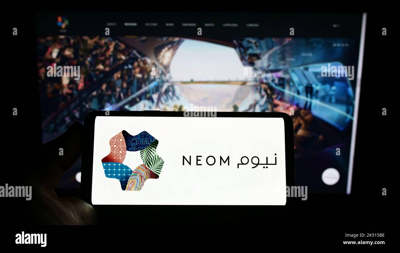 Person, die das Smartphone mit dem Logo des saudischen Immobilienentwicklers NEOM Company auf dem Bildschirm vor der Website hält. Konzentrieren Sie sich auf die Telefonanzeige. Stockfoto