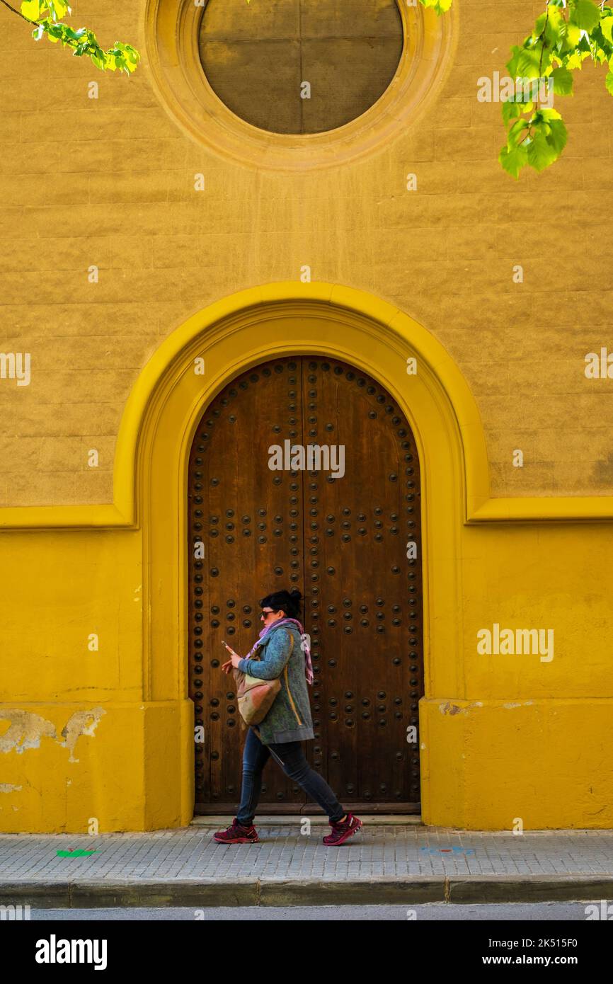 Vilafranca del Penedes, Katalonien, Spanien - 26. April 2022: Frau mit einem Telefon auf dem Hintergrund eines alten gotischen Gebäudes Stockfoto