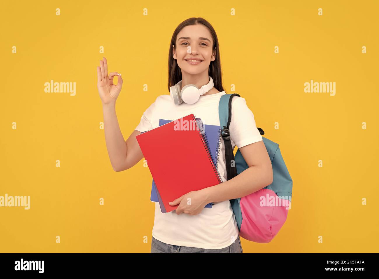Positive Dame in Kopfhörer halten Copybook tragen Rucksack, zurück zur Schule Stockfoto