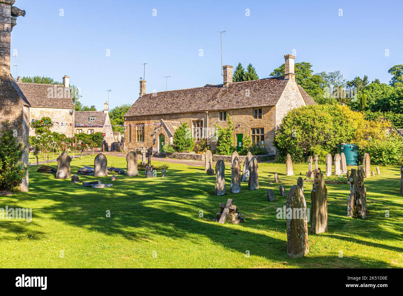 Im Hochsommer wird am frühen Morgen die Grundschule der Church of England aus dem 19.. Jahrhundert im Cotswold-Dorf Bibury, Gloucestershire, England, beleuchtet Stockfoto