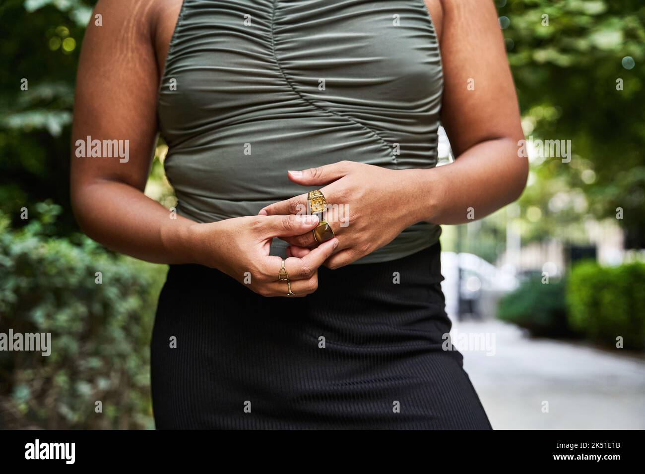 Nicht erkennbare Transgender-Frau mit Dehnungsstreifen an den Armen, die den Ring am Finger anpasst, während sie am Sommertag auf der Parkallee steht Stockfoto
