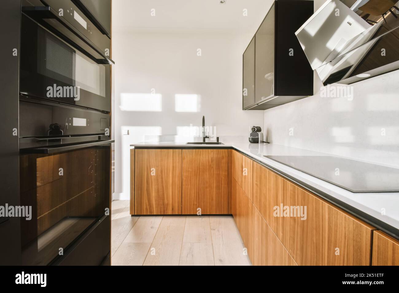 Theke mit modernen Geräten in hellen stilvollen Küche mit Holzschränken und Lichtfenster in der Wohnung platziert Stockfoto