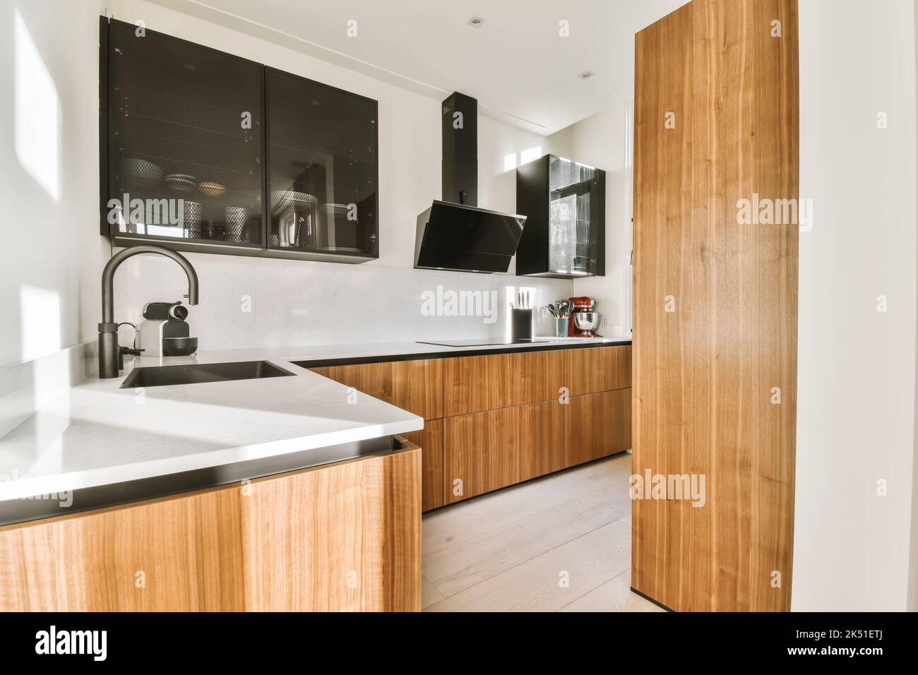 Theke mit modernen Geräten in hellen stilvollen Küche mit Holzschränken und Lichtfenster in der Wohnung platziert Stockfoto