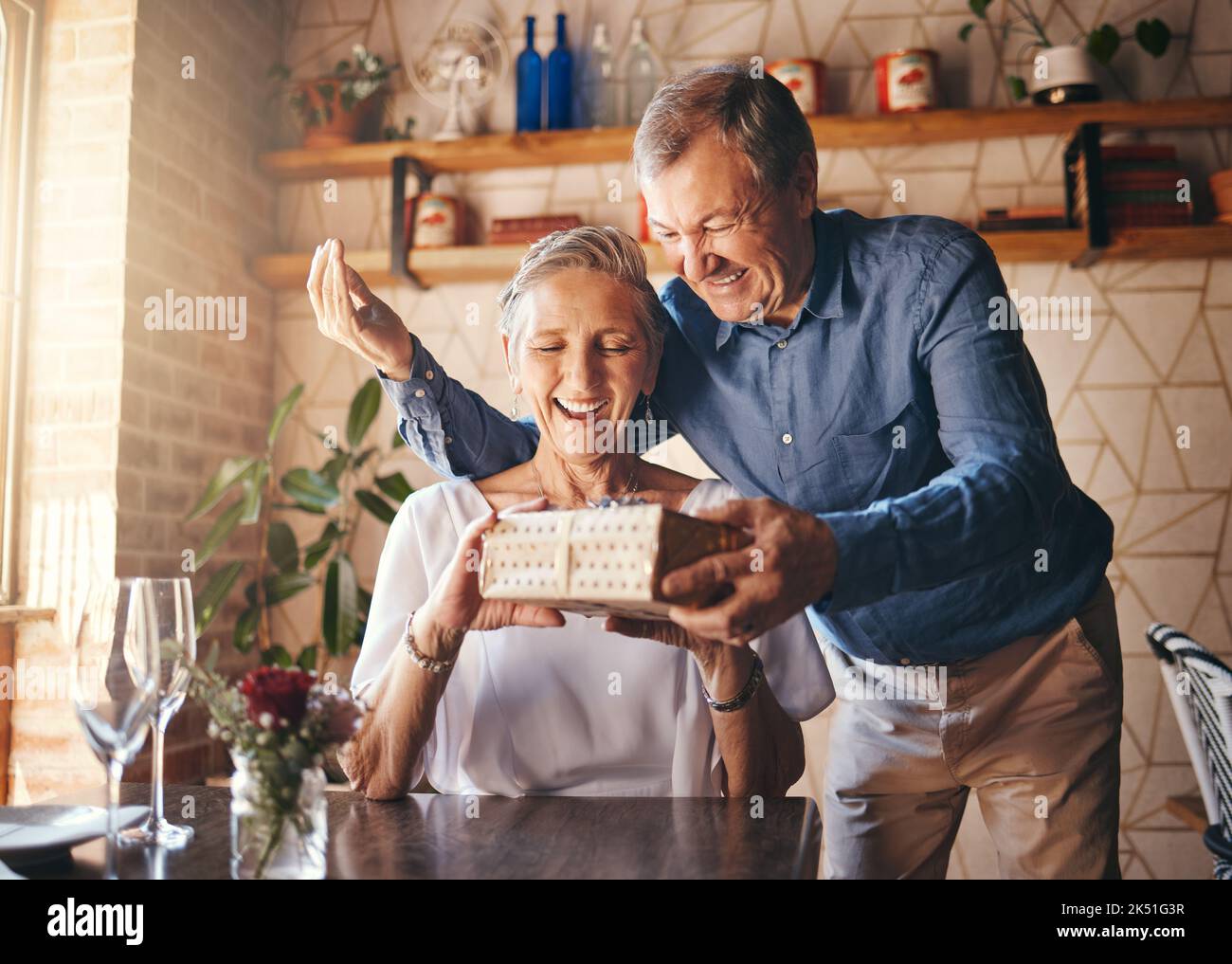 Liebe, Paar ältere Menschen und Geschenk, um Jahrestag am Tag mit einem Lächeln zu feiern, glücklich und aufgeregt zusammen. Romantik, reifer Mann und ältere Frau tauschen sich aus Stockfoto