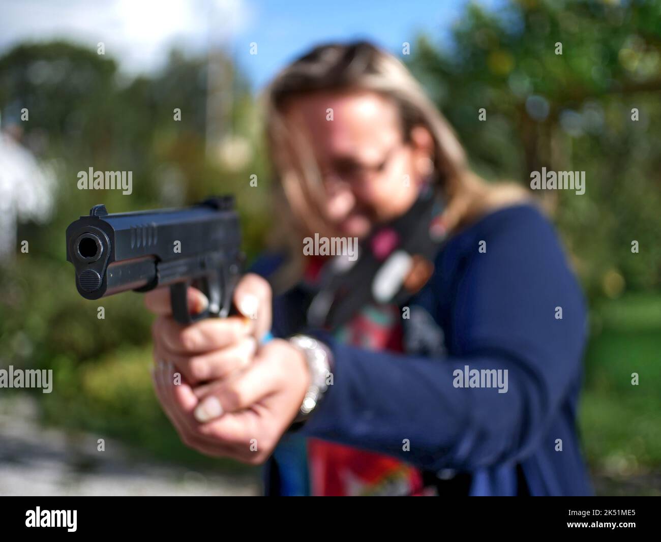 Die Waffe wird von einer blonden Kaukasierin im Freien gehalten. Stockfoto