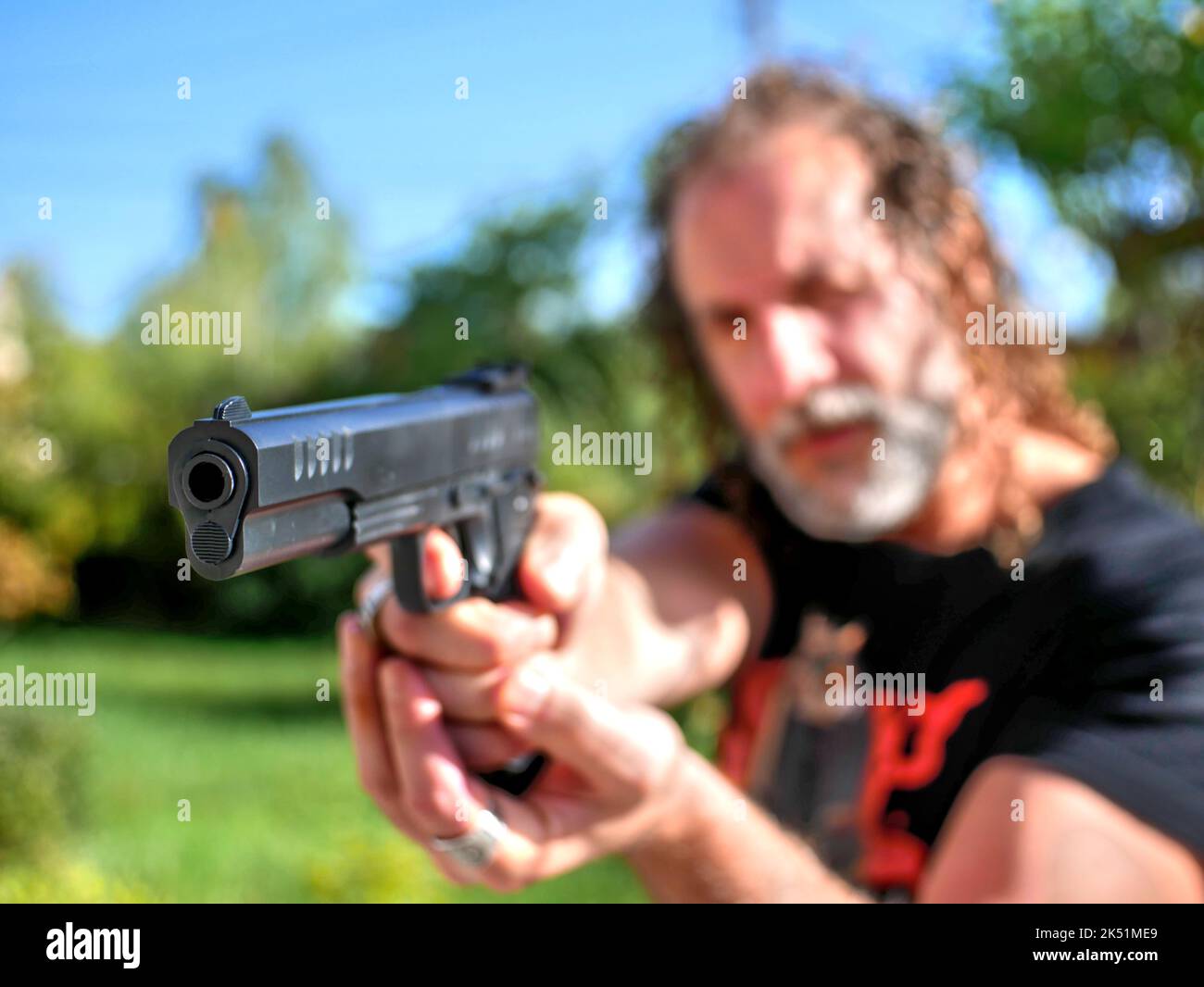 Die Waffe wird von einem verschwommenen kaukasischen Mann im Freien gehalten. Stockfoto