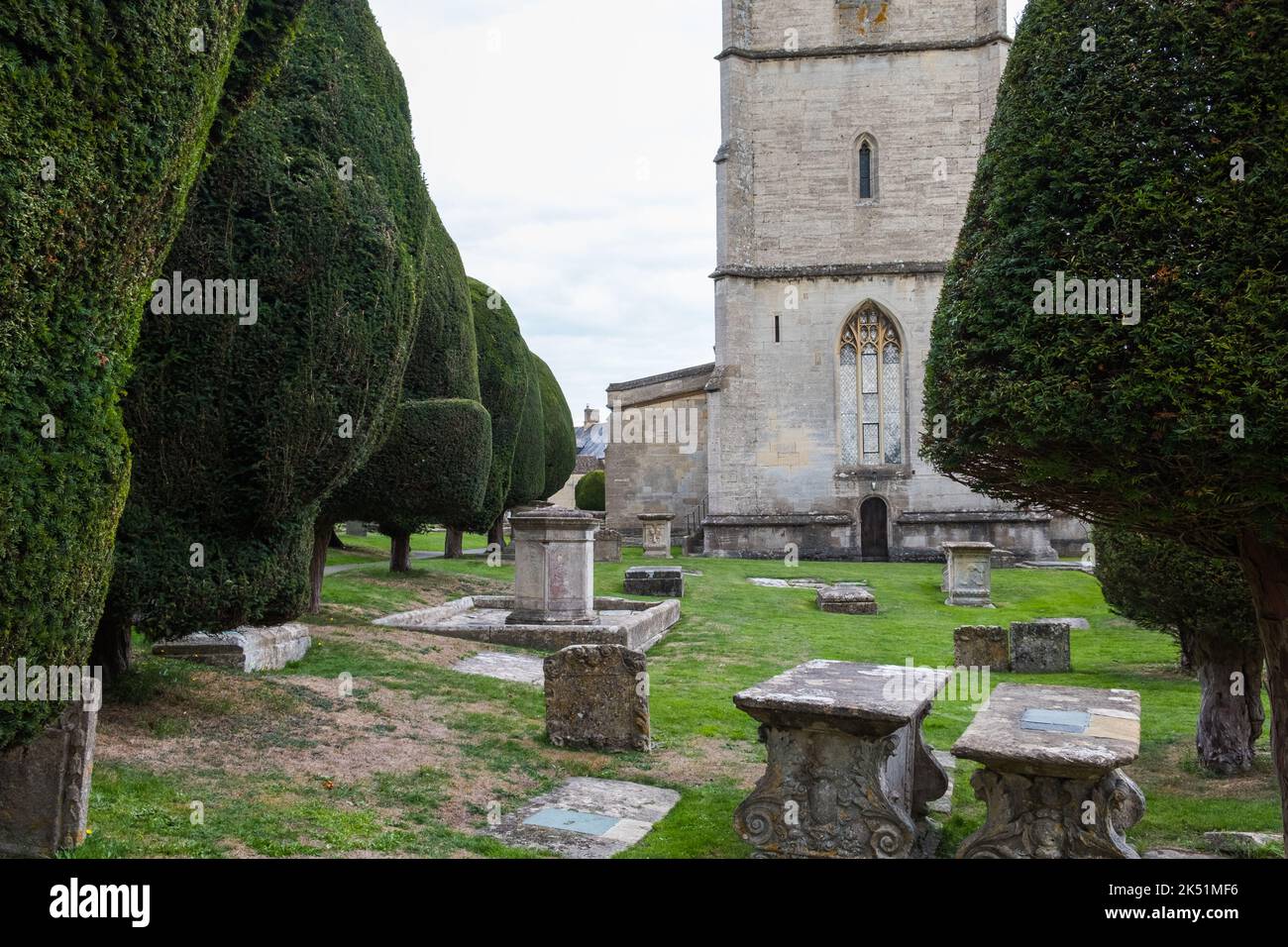 Der Kirchhof in der St. Mary's Church in Painswick, Gloucestershire, ist berühmt für seine Eibenbäume Stockfoto