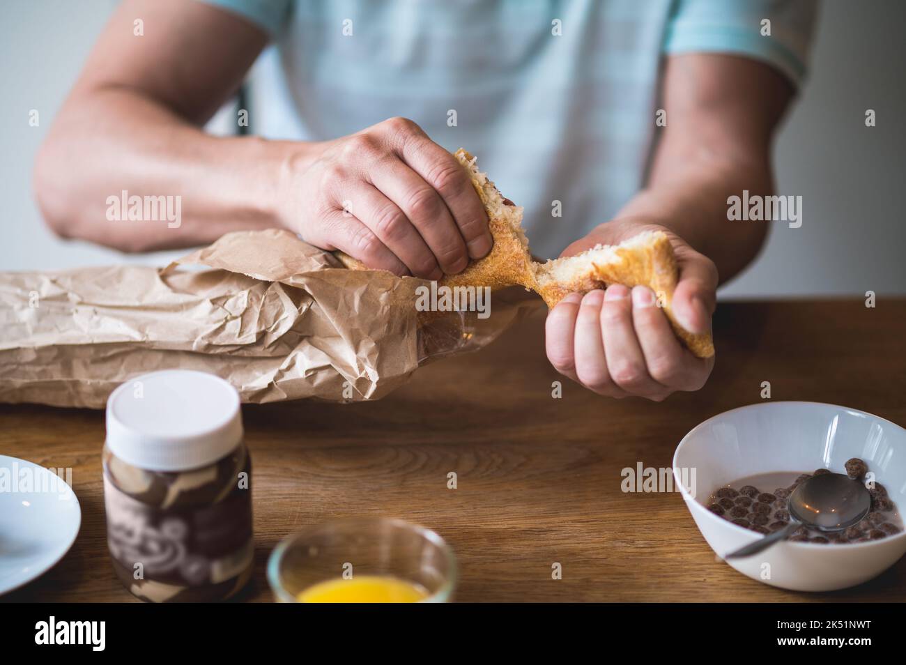 Nahaufnahme des Mannes, der Brot für Sandwiches bricht Stockfoto