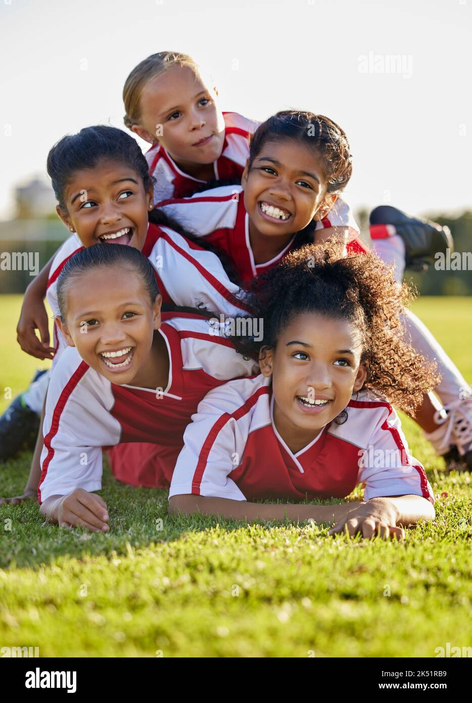 Team, Kinder und glücklich auf dem Feld im Sport nach Sieg in Spiel, Spiel oder Wettbewerb. Mädchen, lächeln und zusammen nach Teamarbeit im Fußball, Fußball oder Stockfoto