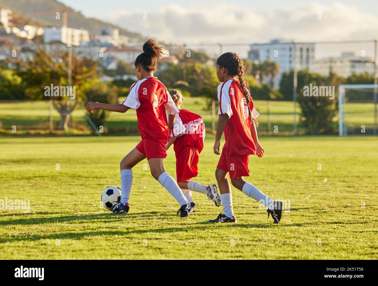 Fußball, Wettkampf- und Fußballathlet oder Teenager-Gruppe spielen Spiel, trainieren und üben auf Gras. Mädchen mit einem Ball laufen, Fitness und Bewegung auf einem Stockfoto