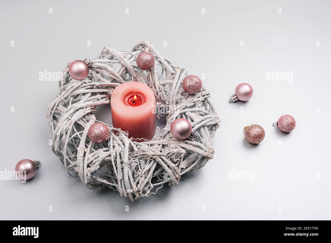 Weihnachtskranz mit rosa Kerze und Kugeln auf silbergrauem Hintergrund. Konzept für Winterferien. Draufsicht. Stockfoto