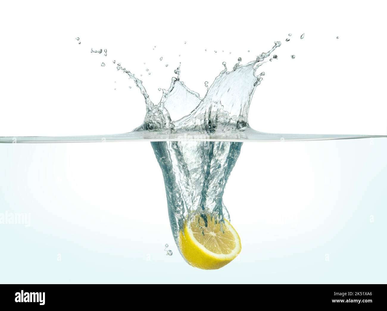 Halbe Zitrone, die in klarem Wasser spritzt. Seitenansicht auf weißem Hintergrund. Stockfoto