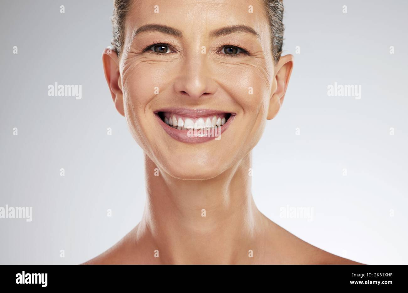 Gesicht, Porträt und Hautpflege für reife Frauen mit einem Lächeln für die Gesichts Gesundheit vor einem grauen Mockup Studio Hintergrund. Ältere Modell glücklich über natürliche Stockfoto
