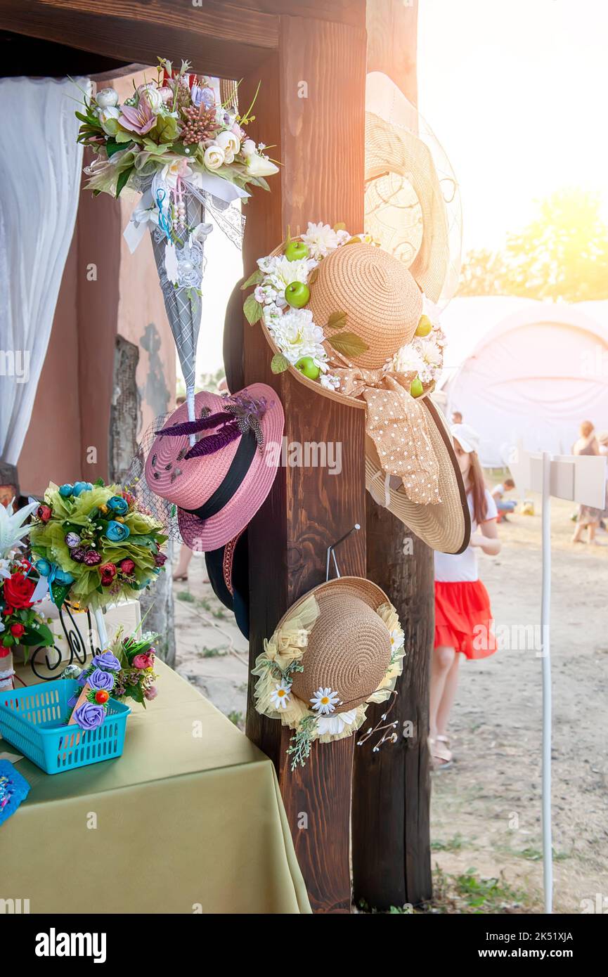 Strohhüte, die mit Blumen am Schaufenster verziert sind. Wunderschöne handgefertigte Produkte. Produkte, Kleinunternehmen Stockfoto