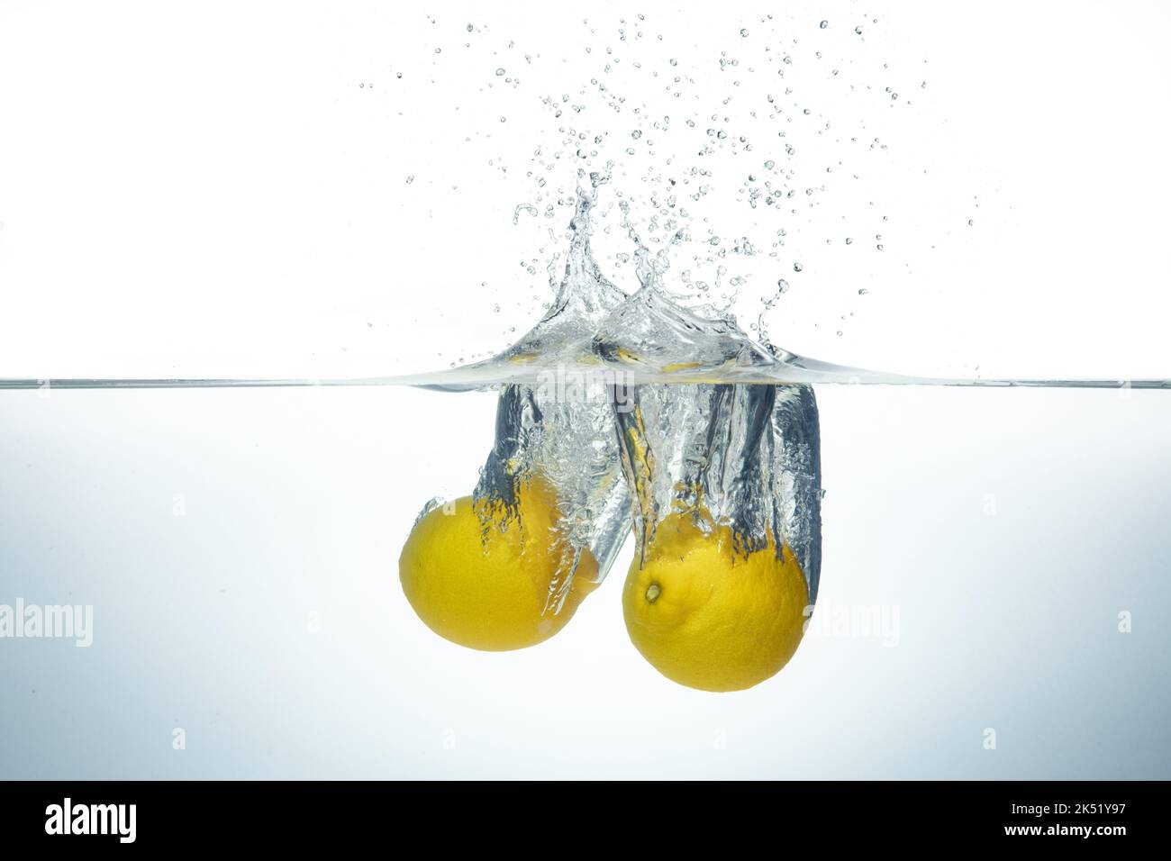 Zwei Zitronen spritzen in klarem Wasser. Seitenansicht auf weißem Hintergrund. Stockfoto