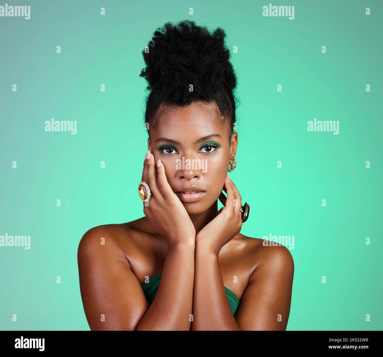 Mode, Schönheit und Make-up mit einer schwarzen Frau oder einem Model im Studio auf einem grünen Hintergrund für Empowerment und Gleichheit. Kosmetik, Hände und trendy mit Stockfoto