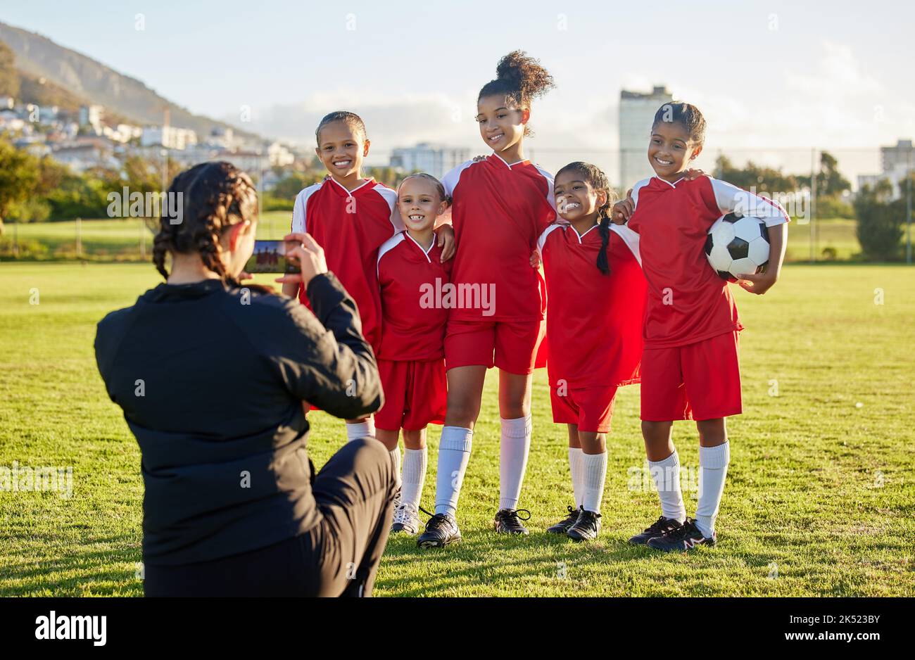 Fußball-, Foto- und Sportcoach mit einer Mädchenmannschaft, die für ein Foto im Freien auf einem Fußballfeld posiert, um Fitness oder Training zu absolvieren. Übung, Teamarbeit und Stockfoto